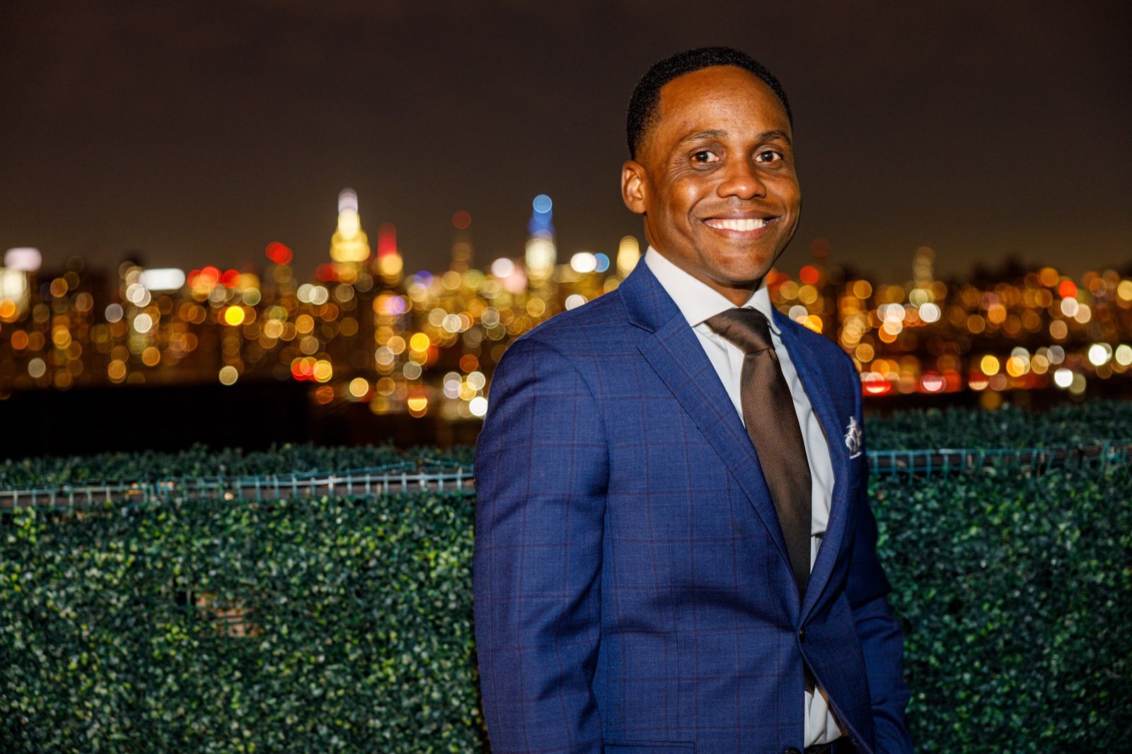 A Gentlemen's Factory member on a Brooklyn rooftop with the NYC skyline at night