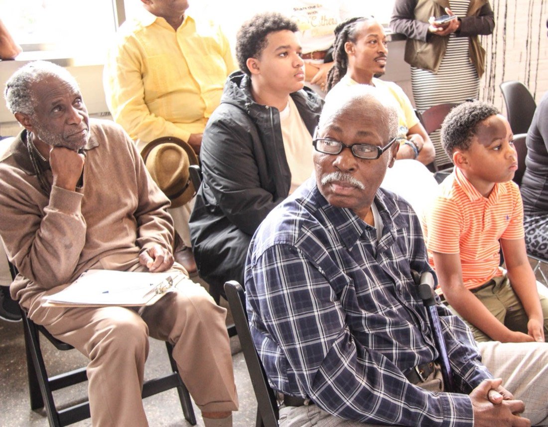Men of several generations listening during a community conversation