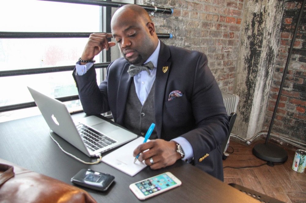 A Gentlemen's Factory member working at his desk with a laptop and notes