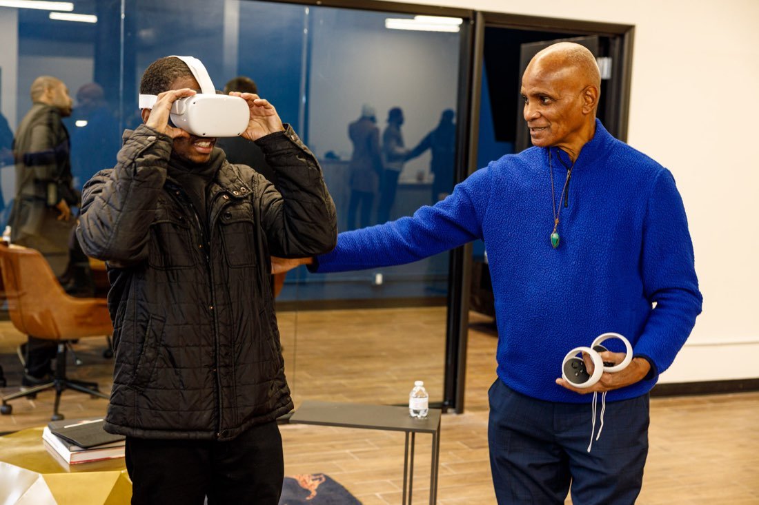 A Gentlemen's Factory mentor guides a young man trying a virtual reality headset