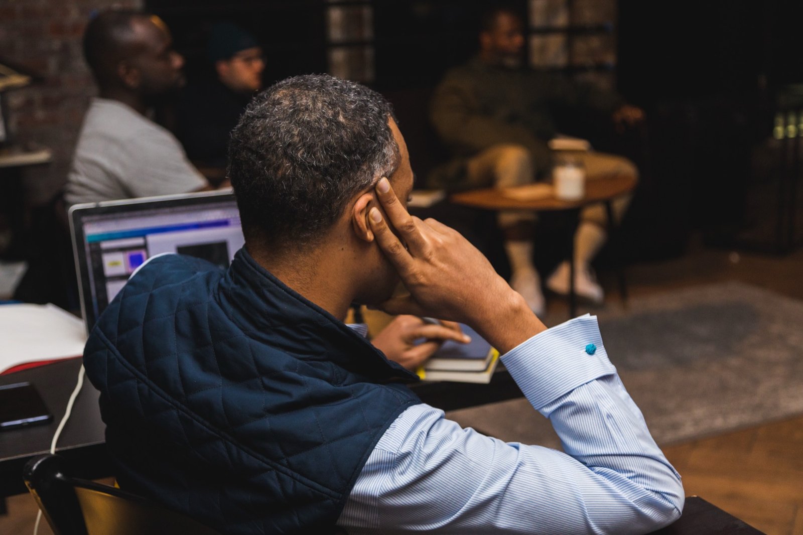 A man deep in thought, writing at his laptop during a Gentlemen's Factory session